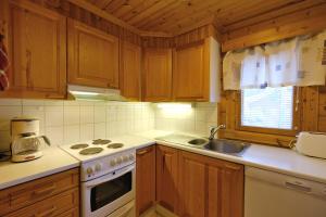a kitchen with wooden cabinets and a stove and a sink at Villiporo Cabin Levi in Levi