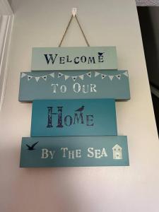 un cartello che dice benvenuto nella nostra casa vicino al mare di Seaside Apartment - 2 storey 2 bedrooms a Ballycastle