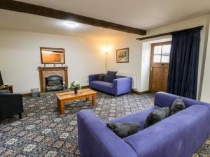 a living room with two purple couches and a fireplace at Byre Cottage in Whitby