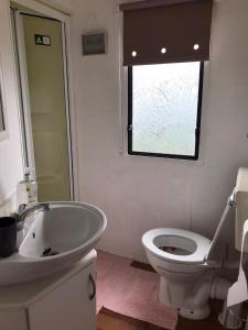 een badkamer met een wastafel, een toilet en een raam bij Melody Brooks Caravan Park in Portknockie