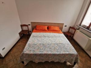 1 dormitorio con 1 cama con almohadas de color naranja y 2 sillas en Appartamento Lucia, en Filattiera