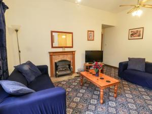 a living room with two blue couches and a fireplace at Forge Cottage in Whitby
