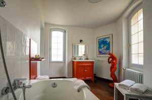 a bathroom with a white tub and a red statue at La Chaumière, Demeure d'hôtes in Lauris