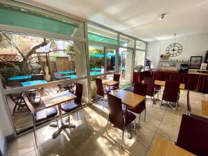 a restaurant with tables and chairs and windows at Hotel Les Grenadines in Cap d'Agde