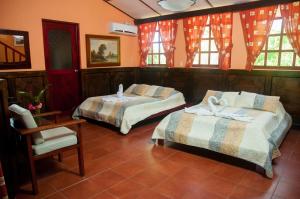 1 dormitorio con 2 camas, silla y ventanas en Hotel Playa Bejuco, en Esterillos Este