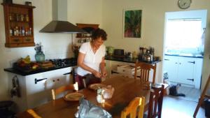 una donna in piedi in una cucina con tavolo di Room @ Irissa Sanctuary a De Rust