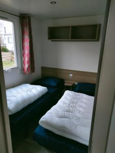 een kleine kamer met 2 bedden en een raam bij BJ Chalets - Robbengat 68 - Gezellige, kindvriendelijke chalet op vakantiepark Lauwersoog! Vroege incheck! in Lauwersoog