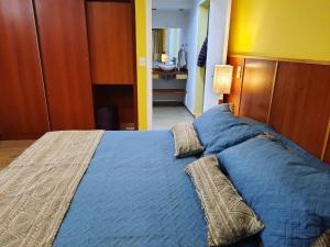 Un dormitorio con una cama azul con almohadas. en Villa Amancay Lake en Dina Huapi