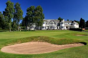 un campo da golf con una grande casa sullo sfondo di Pinewood Cotage - Country Walks and Relaxation a Blairgowrie