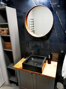 uma casa de banho com um lavatório preto e um espelho em Apartament Sand&Blue em Sztutowo