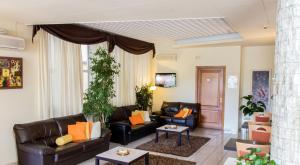 a living room with black leather furniture and orange pillows at Park Hotel in Montecatini Terme