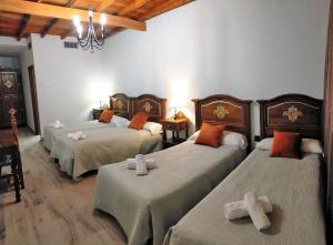 a room with three beds and a chandelier at Hotel El Mirador in Alhaurín el Grande