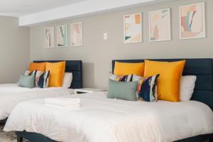 two beds with orange and blue pillows in a room at The Beverly in Beverly
