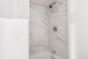 a bathroom with a shower with white marble walls at The Beverly in Beverly
