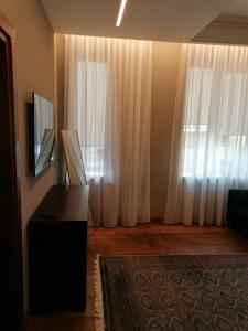 a living room with white curtains and a television at Cathedral Apartments in Kaunas