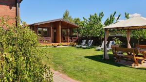 a garden with a gazebo and chairs and a house at Žuvėdrų kiemelis in Šventoji +43 photos
