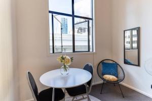 una mesa blanca con sillas y un jarrón de flores. en Bright CBD Studio -Near SkyTower - WiFi - Cityscape, en Auckland