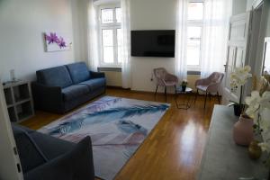 uma sala de estar com um sofá azul e cadeiras em Casa Rudy em Bolzano