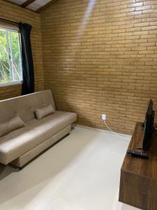 ein Wohnzimmer mit Sofa und Ziegelwand in der Unterkunft Chalés Bem-me-quer Itaipava in Itaipava