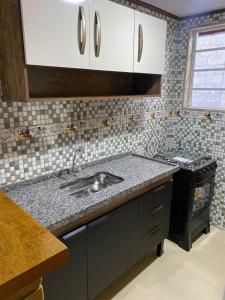 a kitchen with a sink and a stove at Chalés Bem-me-quer Itaipava in Itaipava