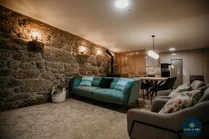 ein Wohnzimmer mit einer Couch und einer Steinwand in der Unterkunft Refúgio do Abade in Terras de Bouro