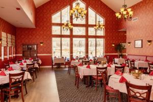 a restaurant with white tables and chairs and a large window at Wine Country Inn in Palisade