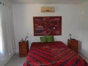 een slaapkamer met een bed met een rood dekbed bij Residência Colibri apto 07 in Porto Seguro