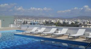 a group of white lounge chairs next to a swimming pool at STAY Eden Beach Studio in Limassol