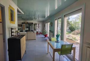 a large kitchen with a glass table and green chairs at La Vie Est Belle, Chambre privée dans une villa in Trets