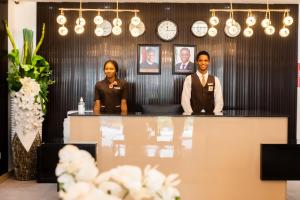Isglo Hotels Ikoyi في لاغوس: رجل وامرأة يقفان في مكتب الاستقبال