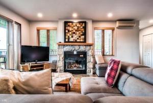 - un salon avec un canapé et une cheminée dans l'établissement Hauts-bois Ski Inout 2brs Wpool Access 193-1, à Mont-Tremblant