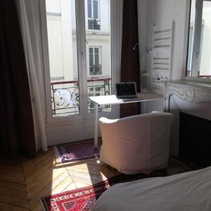 um quarto com uma cama e uma secretária com um computador portátil em Plein centre em Paris