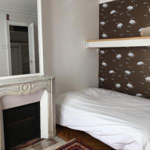 1 dormitorio con chimenea y 1 cama con espejo en Plein centre, en París