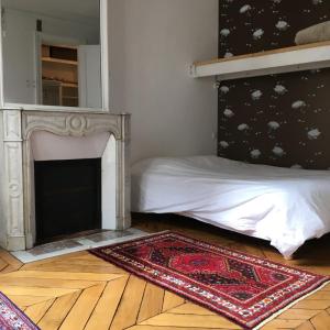 1 dormitorio con 1 cama con chimenea y alfombra en Plein centre, en París