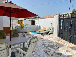 eine Terrasse mit einem Tisch, Stühlen und einem Sonnenschirm in der Unterkunft The Compound in Bijilo