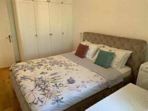 a bed with a floral comforter and pillows on it at Alex Apartments in Budva