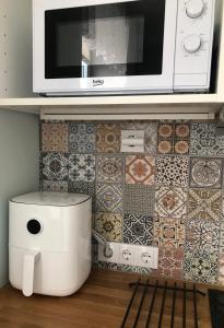 a kitchen with a microwave and a tile wall at Niine apartment 12 in Haapsalu