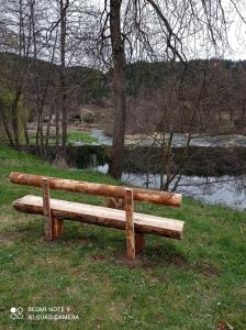 um banco de madeira sentado na relva ao lado de um rio em Auberge du pèlerin em Saint-Vincent