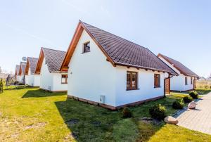 a row of white houses with brown roofs at Bursztynowy Zakątek Domki in Grzybowo