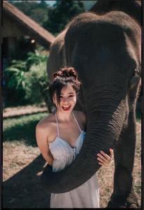 3 Pok Maewang jinxiang Gold elephant park في Ban Mae Sapok Noi: امرأة تعانق شنطة فيل