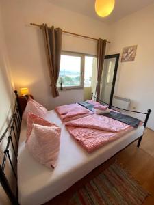 1 dormitorio con cama con sábanas rosas y ventana en Palmgarden Apartments Opatija-Ičići, en Opatija