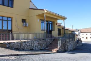 a yellow house with stairs and a stone wall at NUESTRA SEÑORA DEL PINAR in Galve de Sorbe