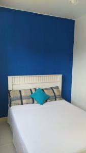 a blue bedroom with a white bed with a blue wall at Cantinho Xodó in Capitólio
