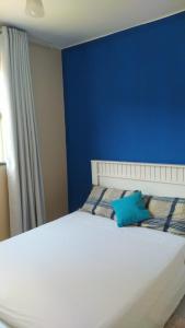 Dormitorio azul con cama blanca y pared azul en Cantinho Xodó en Capitólio