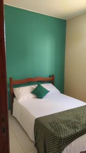 a bedroom with a white bed with a blue wall at Cantinho Xodó in Capitólio