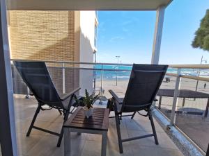 2 Stühle und ein Tisch auf einem Balkon mit Strandblick in der Unterkunft Pineda Beach 221 in La Pineda
