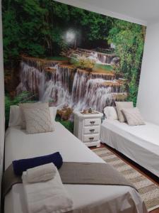 two beds in a room with a waterfall mural at AGRADABLE CASA CON PISCINA EN GONDOMAR(VAL MIÑOR) in Pontevedra