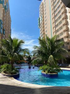 a swimming pool with palm trees in the middle of buildings at Olímpia Park Resort Apto in Olímpia