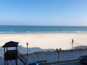 a beach with two people walking on the sand at WAVE 4 Apartments Mamaia Nord in Năvodari