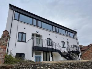 a white house with black windows and a staircase at Lees Lookout Holt ,2 bedroom luxury apartment with private parking in Holt